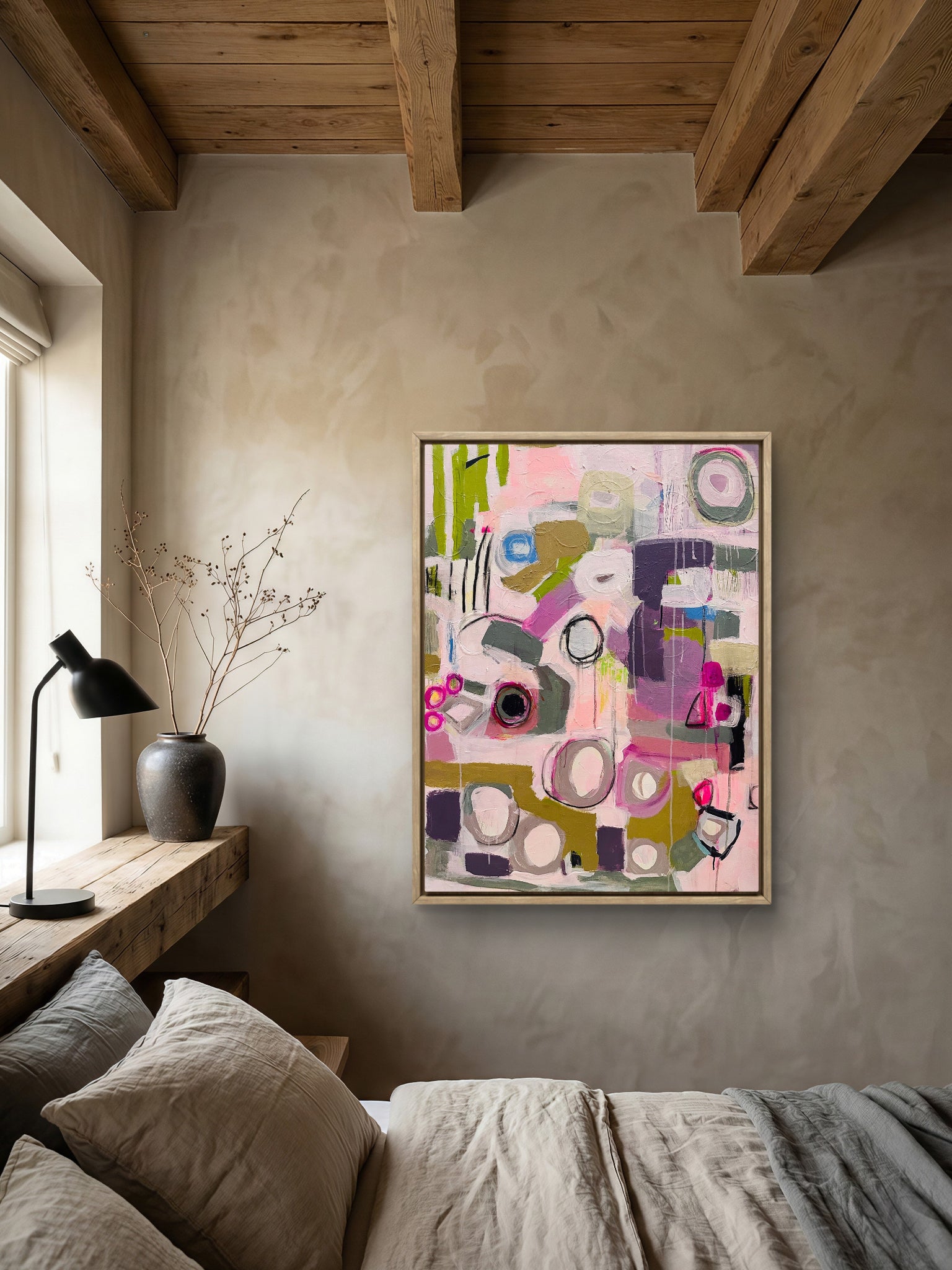 Abstract painting on a wall in a room with a bed and lamp.